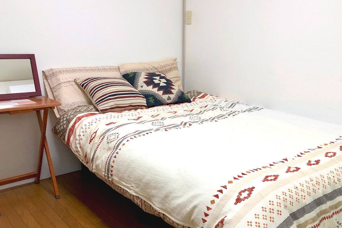 A single bed with patterned bedding, a bedside table, and a mirror.