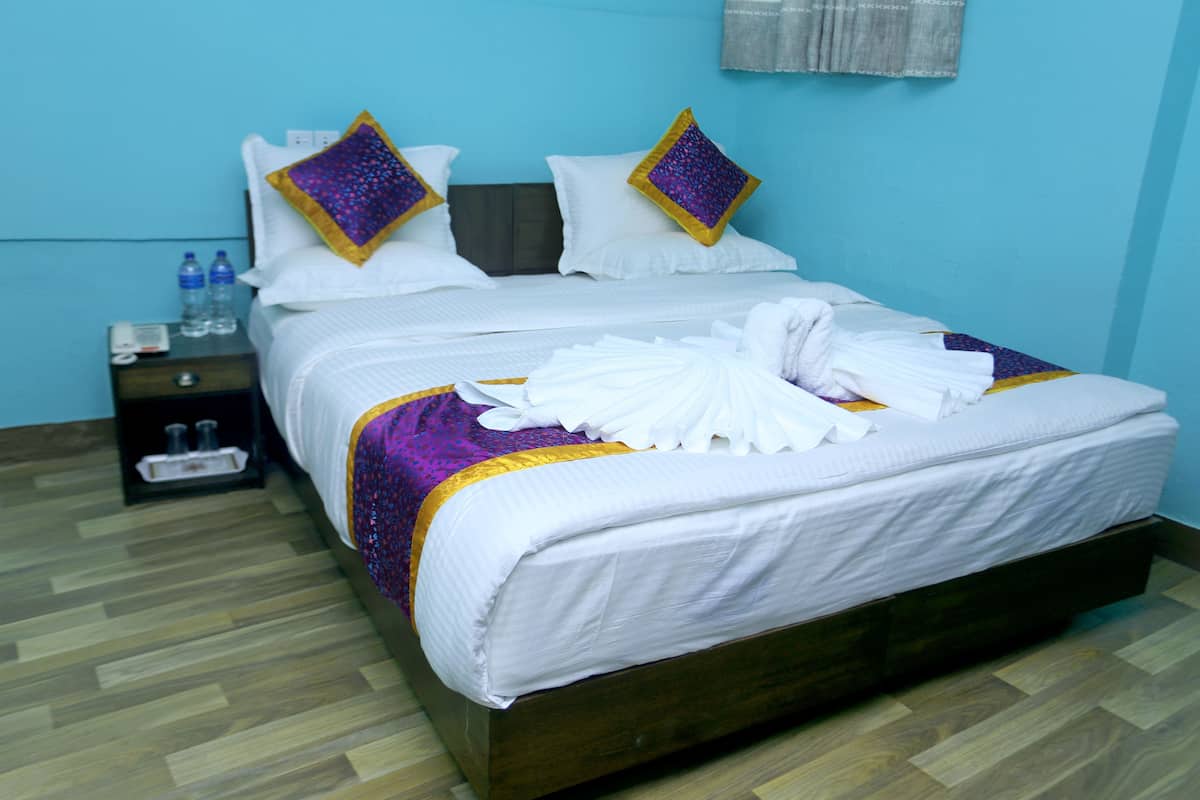 A neatly made bed with white linens, two decorative pillows, and a folded towel on the bed.