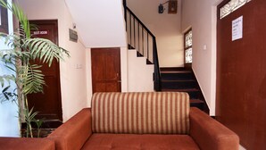 Una escalera con barandilla, una puerta de madera con la leyenda 'REST ROOM' y un letrero que indica zona de lavandería y tintorería.
