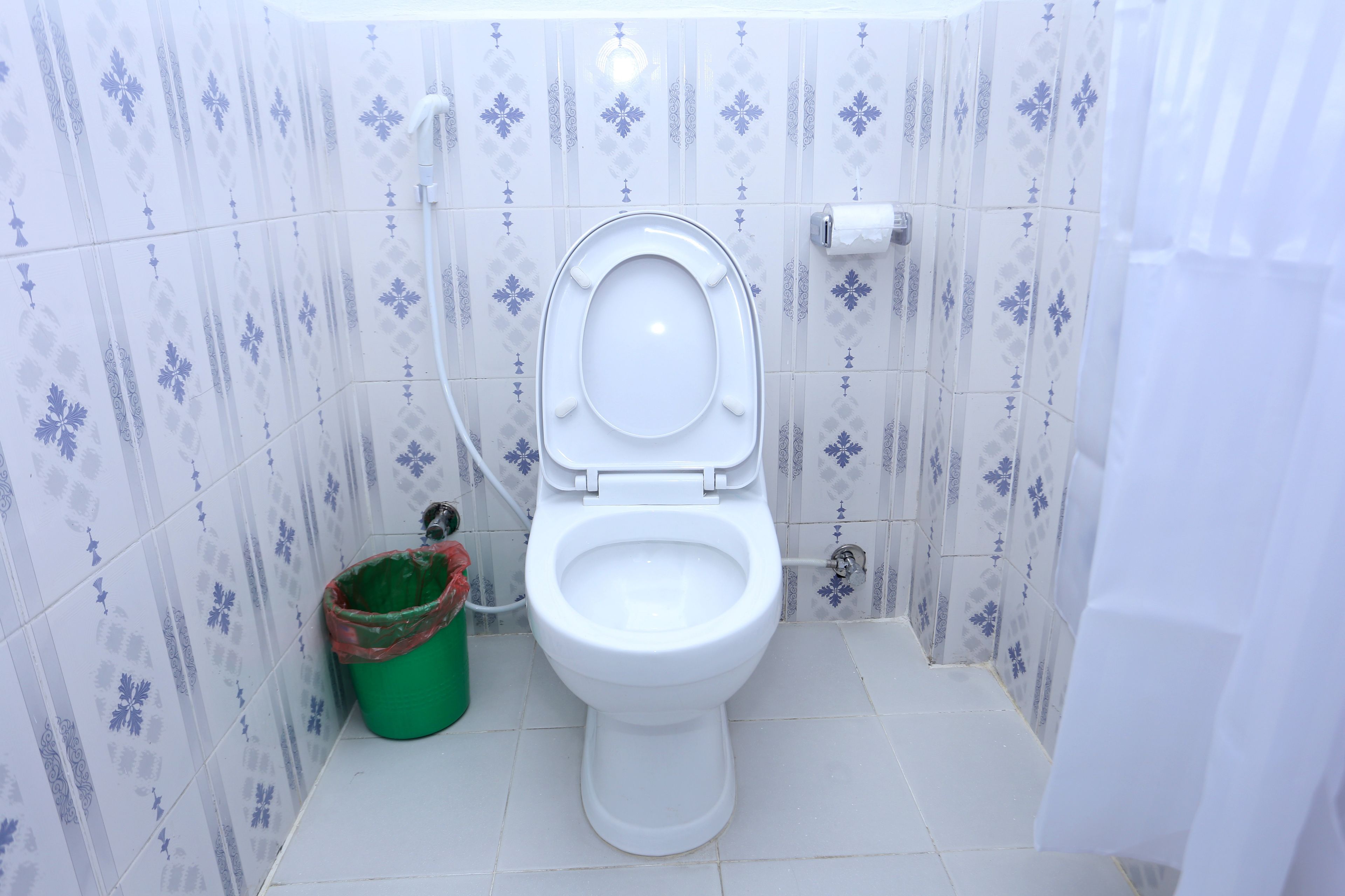 A white toilet with a closed seat in a bathroom with patterned tiles.