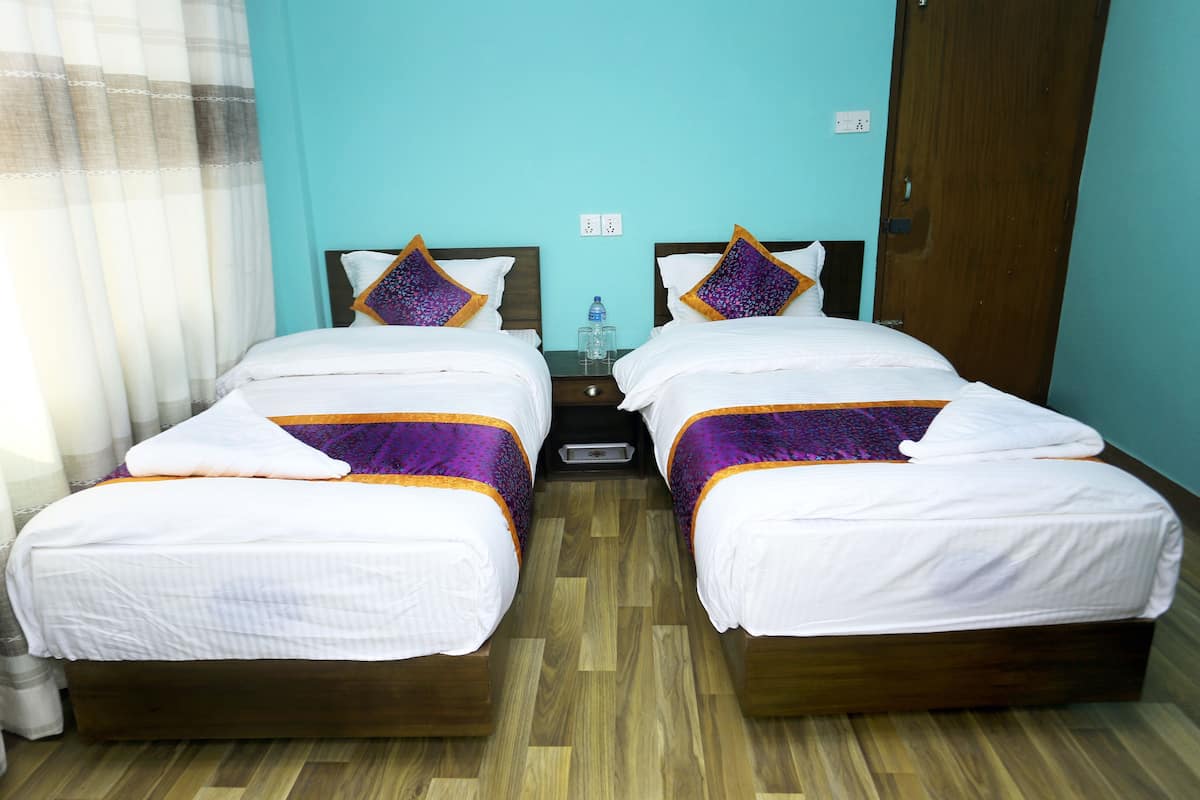 A twin room with two beds, a nightstand, a water bottle, and a power outlet.