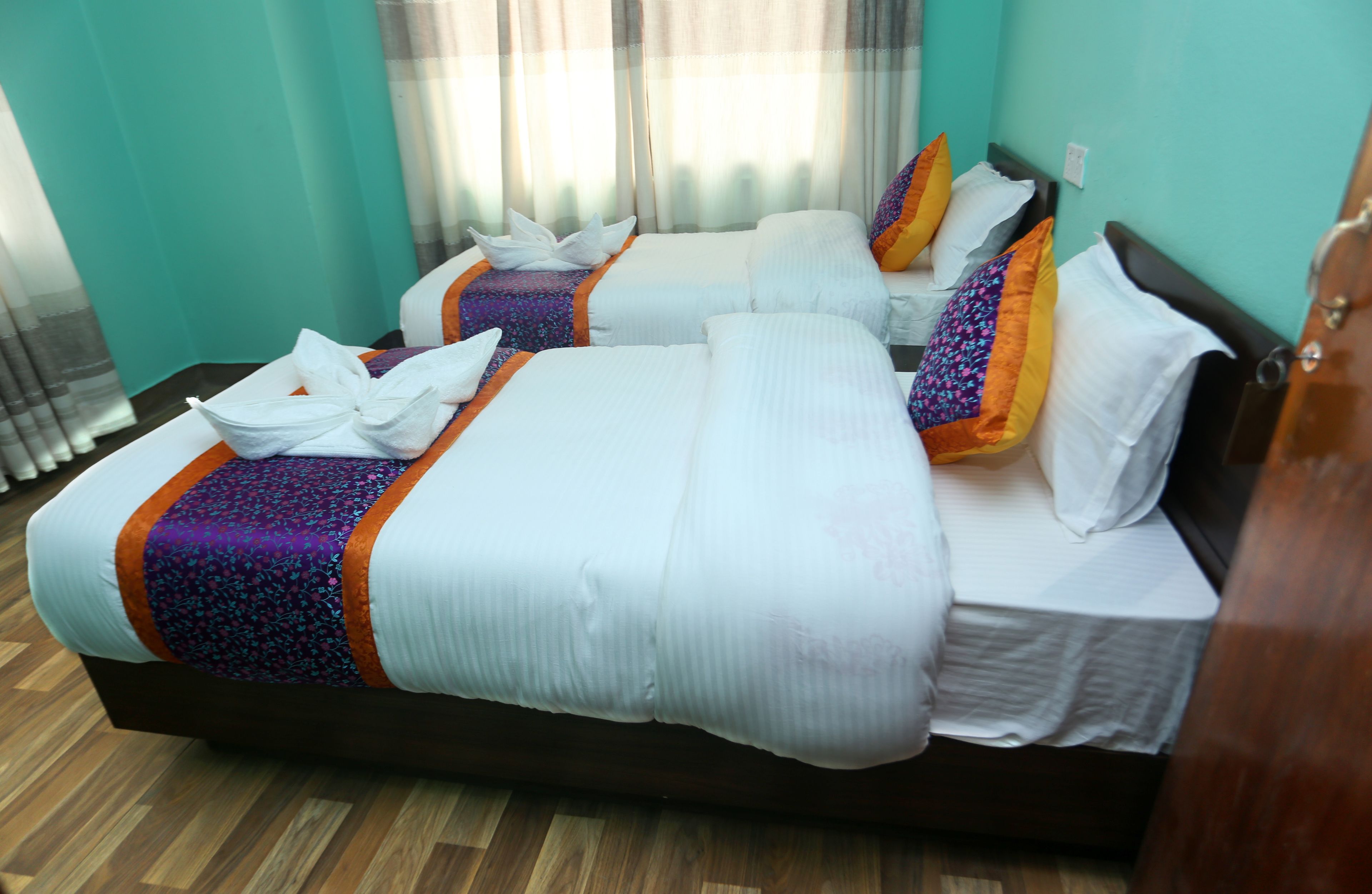 Une chambre d’hôtel avec deux lits, chacun agrémenté de draps blancs et d’oreillers colorés.