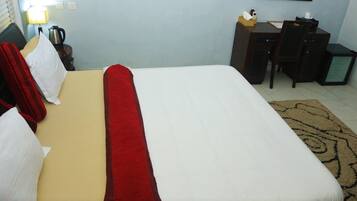 A hotel room with a bed, a desk, a chair, and a small cabinet.