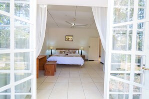 Ein Schlafzimmer mit einem Bett, Nachttischen, einem Deckenventilator und einem Fenster mit Vorhängen.
