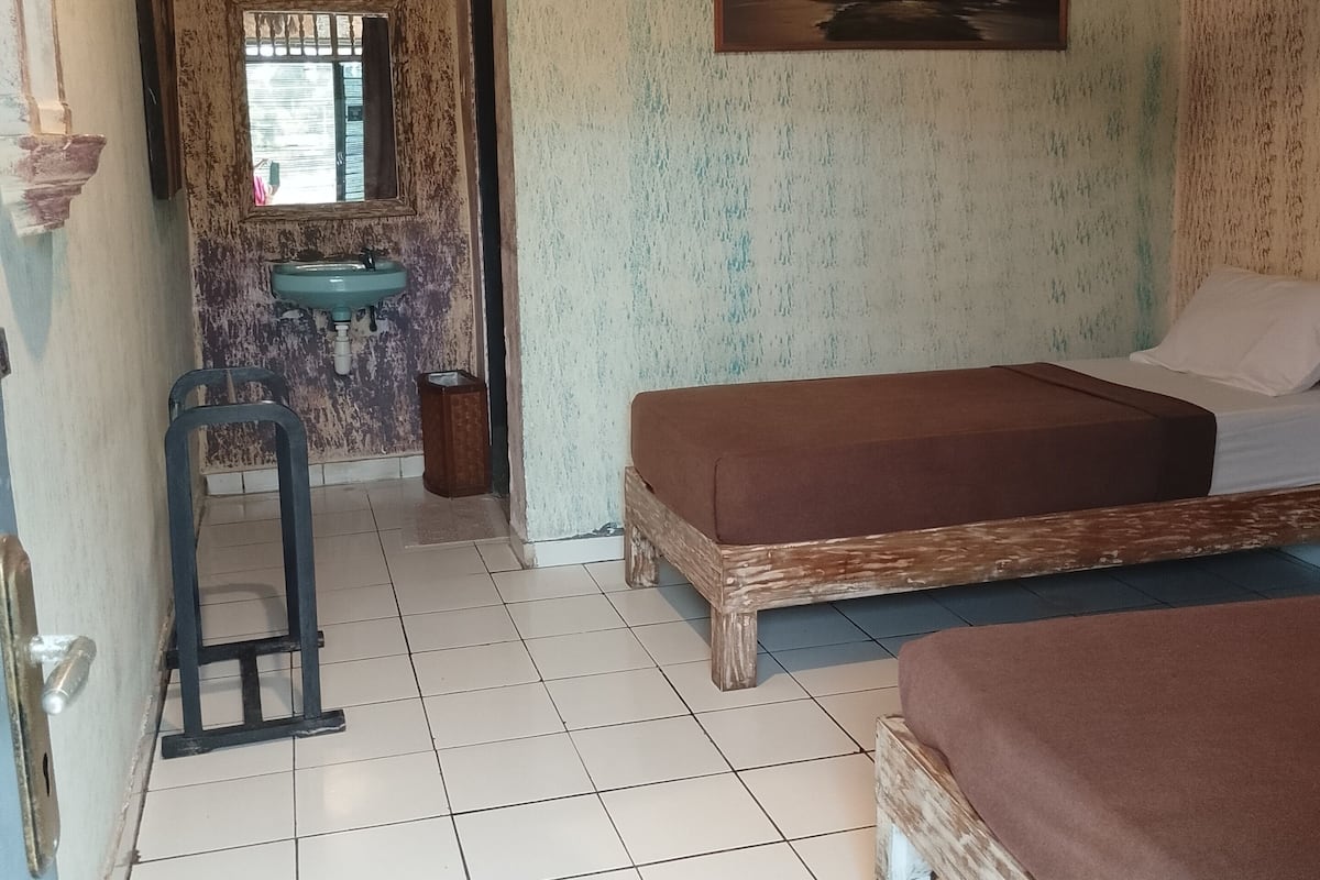 A room with two beds, a sink, a window, and a painting on the wall.
