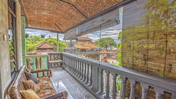Un balcón con techo tejido, un banco acolchado y vistas a edificios tradicionales.