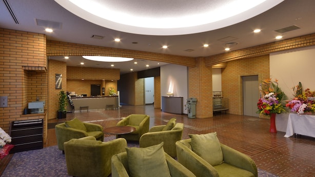 A lobby with green armchairs, a reception desk, and a large circular light fixture. - PRINCE HOTEL Second View MURORAN (Muroran)