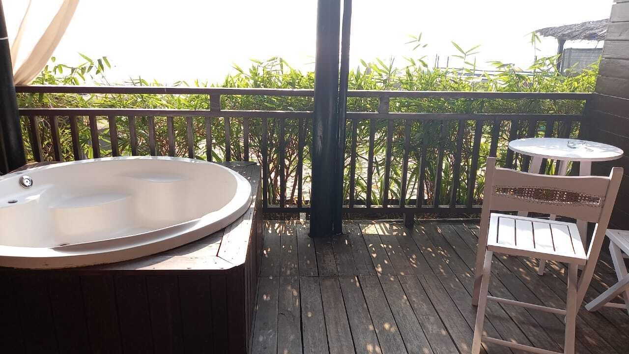 A wooden deck with a hot tub and a small table and chair.