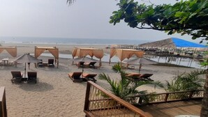 Un espace aménagé au bord de la plage, avec une statue de Bouddha, des chaises longues et des parasols.