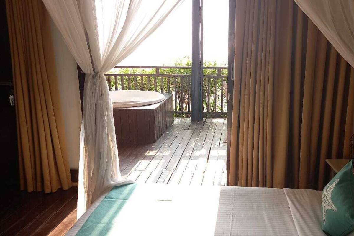 Une chambre avec vue sur une terrasse en bois et un espace salon extérieur.