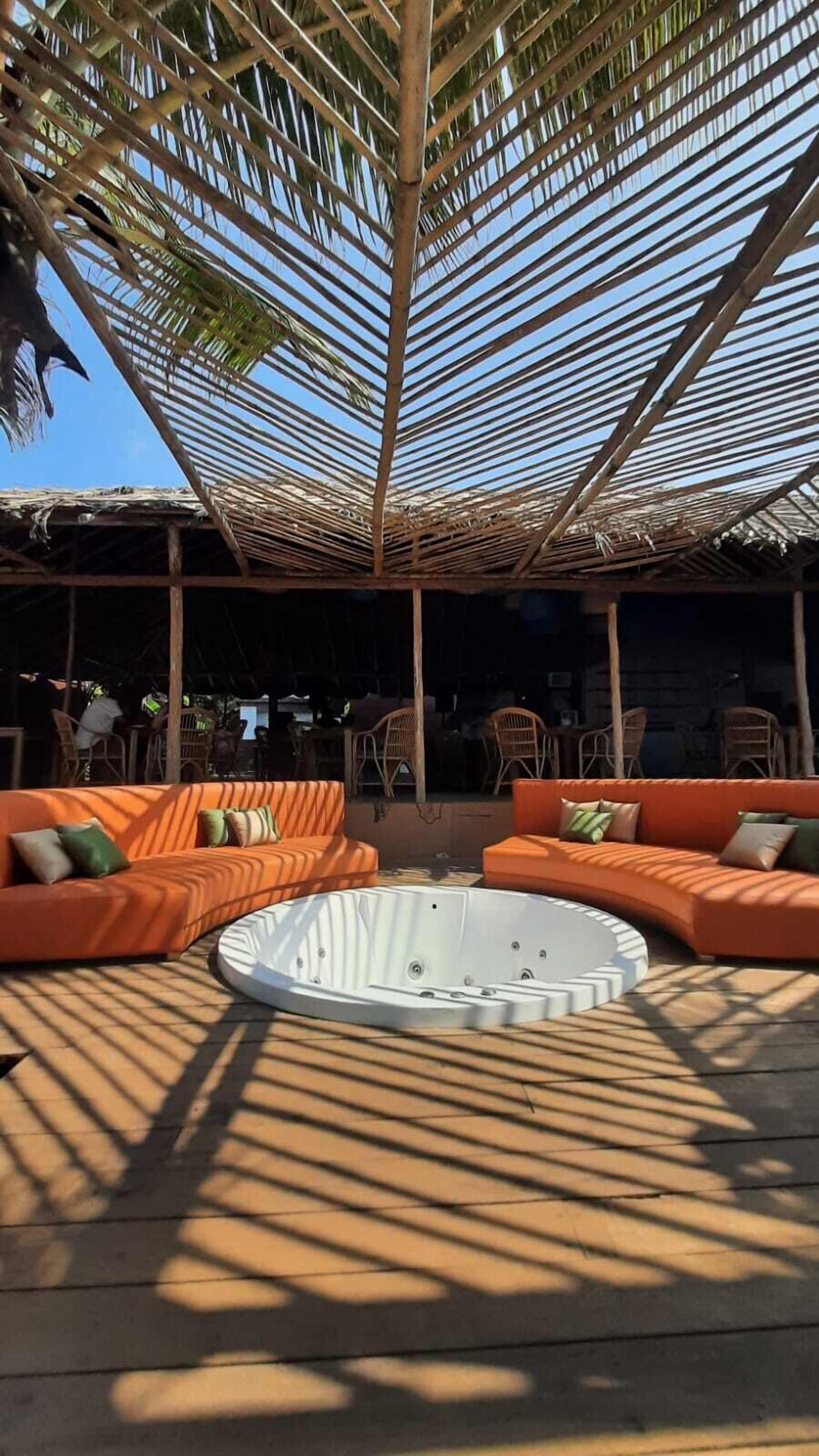 Un área de estar al aire libre con sofás naranjas y un jacuzzi.