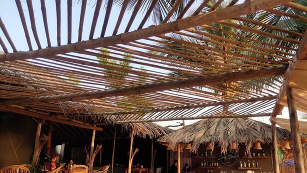 Un espace bar extérieur agrémenté de structures en bambou, de meubles en osier et d’un comptoir.