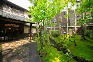 Un bâtiment de style japonais traditionnel, avec un chemin de pierre menant à une porte en bois.