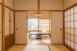 Una habitación japonesa tradicional con suelo de tatami, puertas shoji y un acceso corredizo a vistas del exterior.