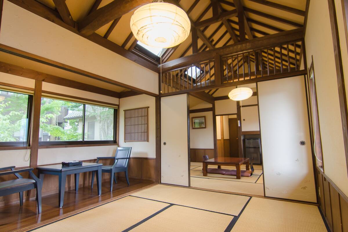 A traditional Japanese room with tatami flooring, wooden furniture, and a view of the outdoors.