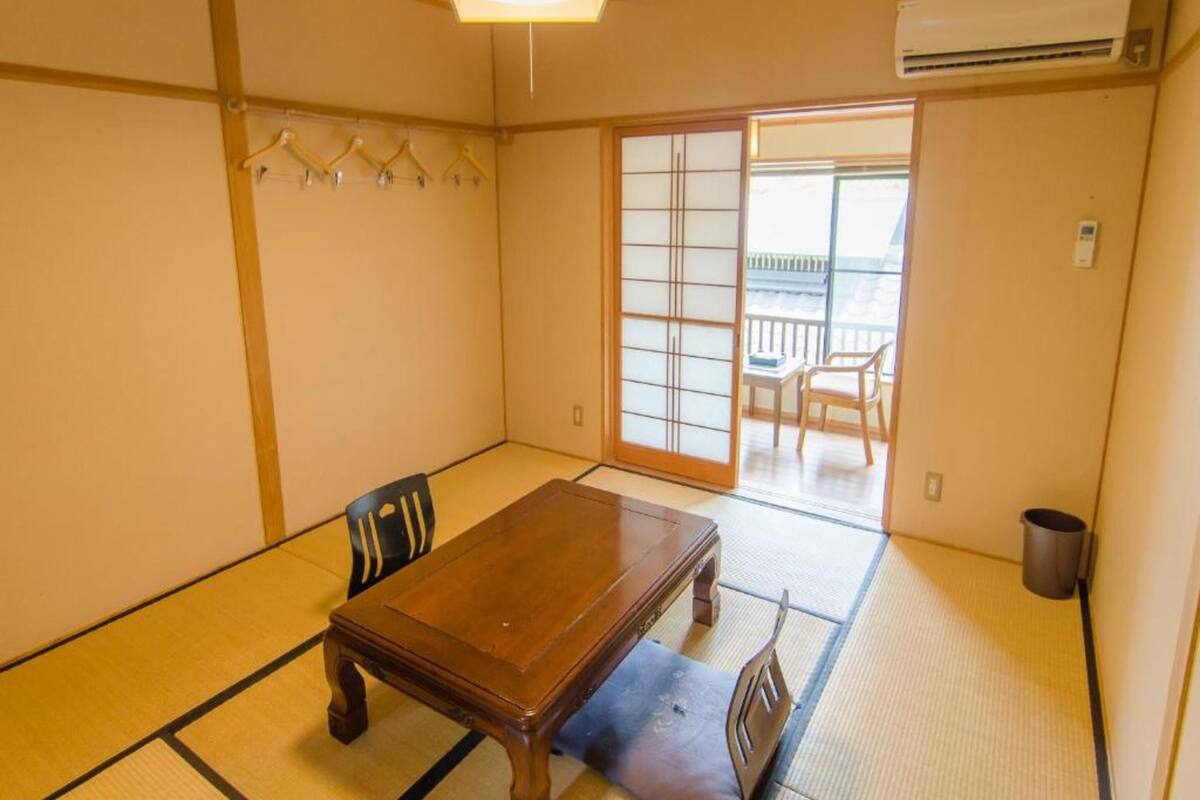 A traditional Japanese room with tatami flooring, a wooden table, and a sliding door leading to a balcony.