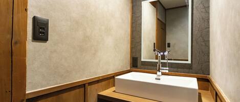 A bathroom with a white sink, a mirror, and a wooden vanity.