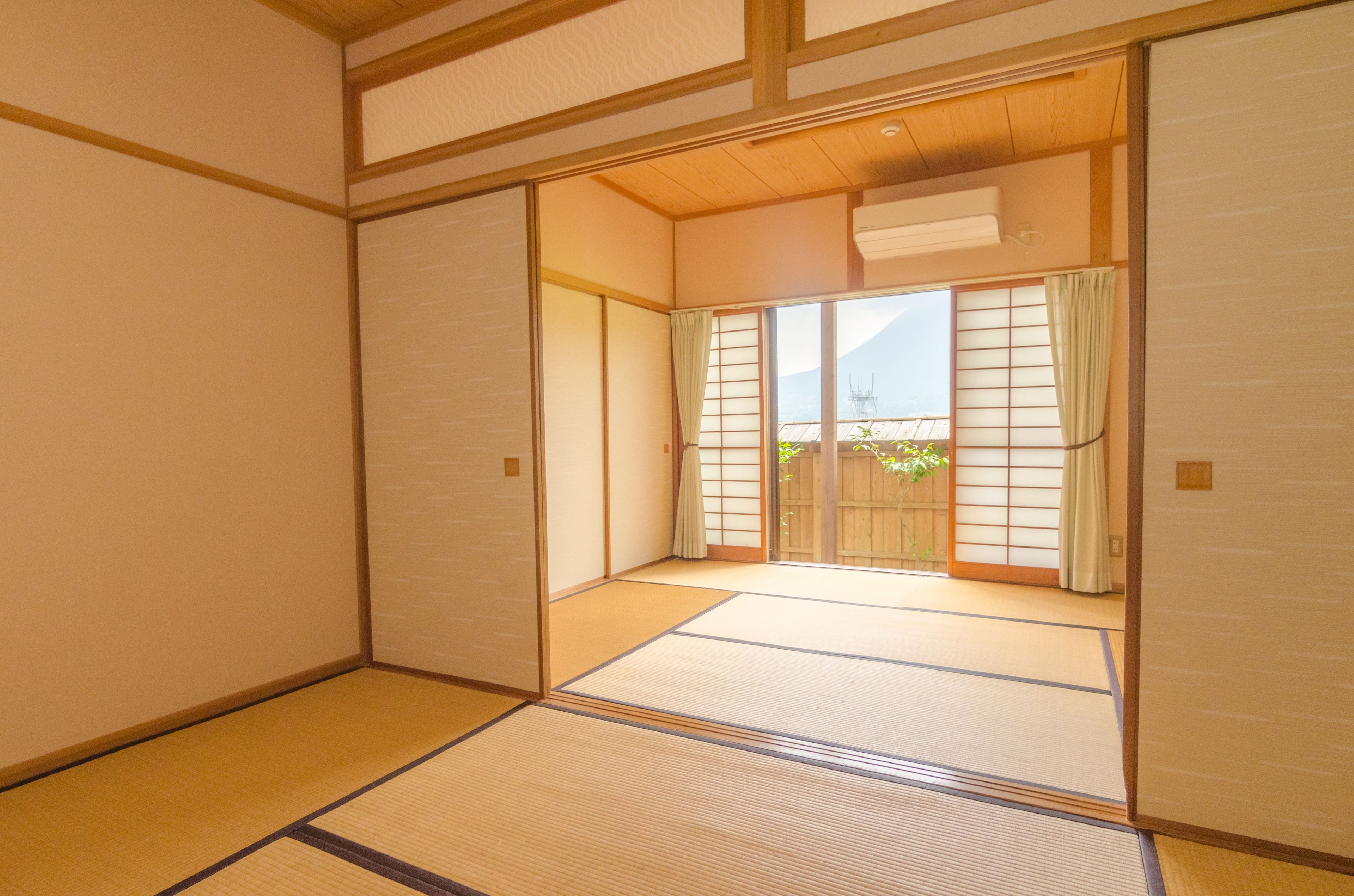 A traditional Japanese room with tatami flooring, sliding doors, and a view of a garden.