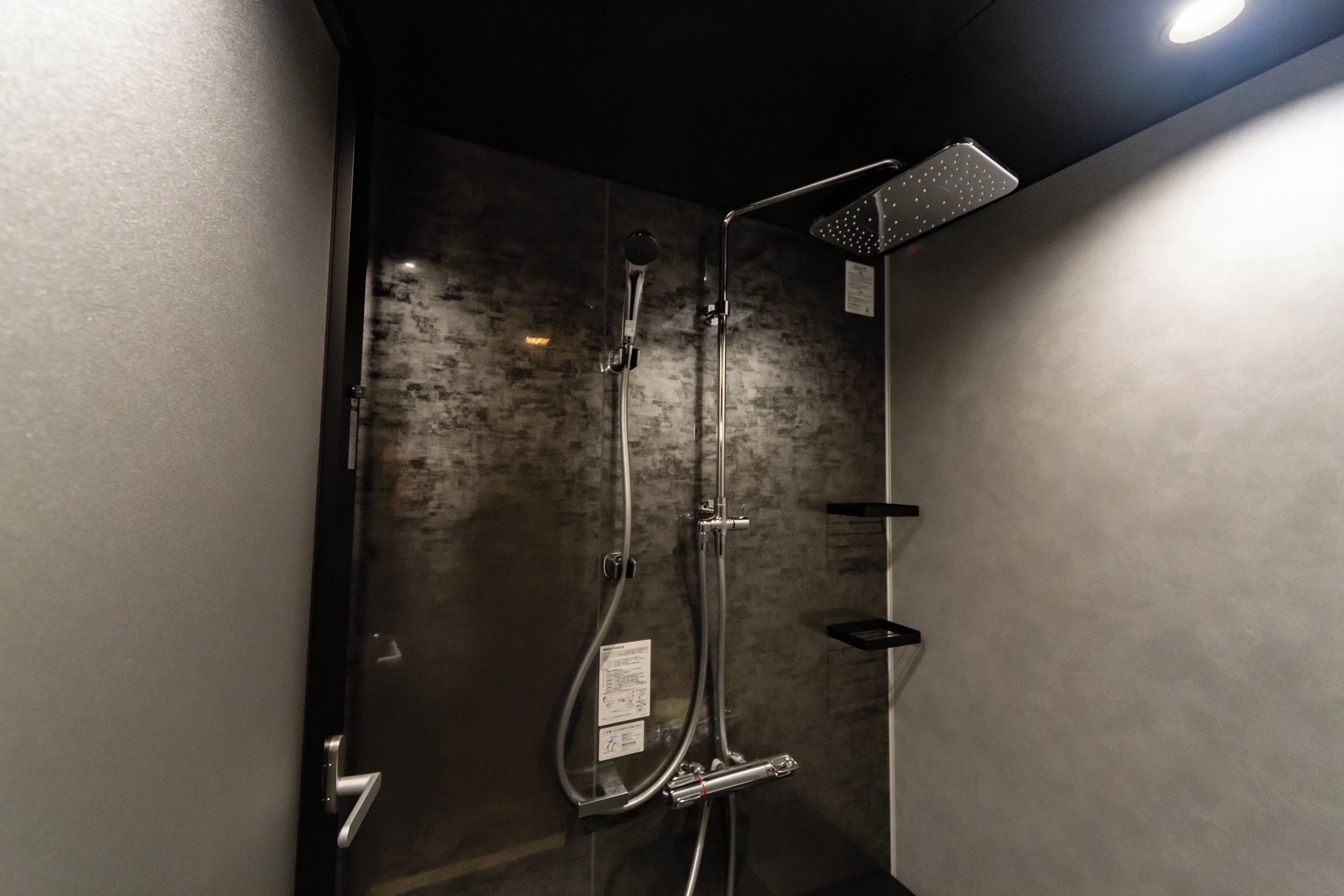 A shower with a handheld showerhead, a wall-mounted rain showerhead, and a handheld showerhead.