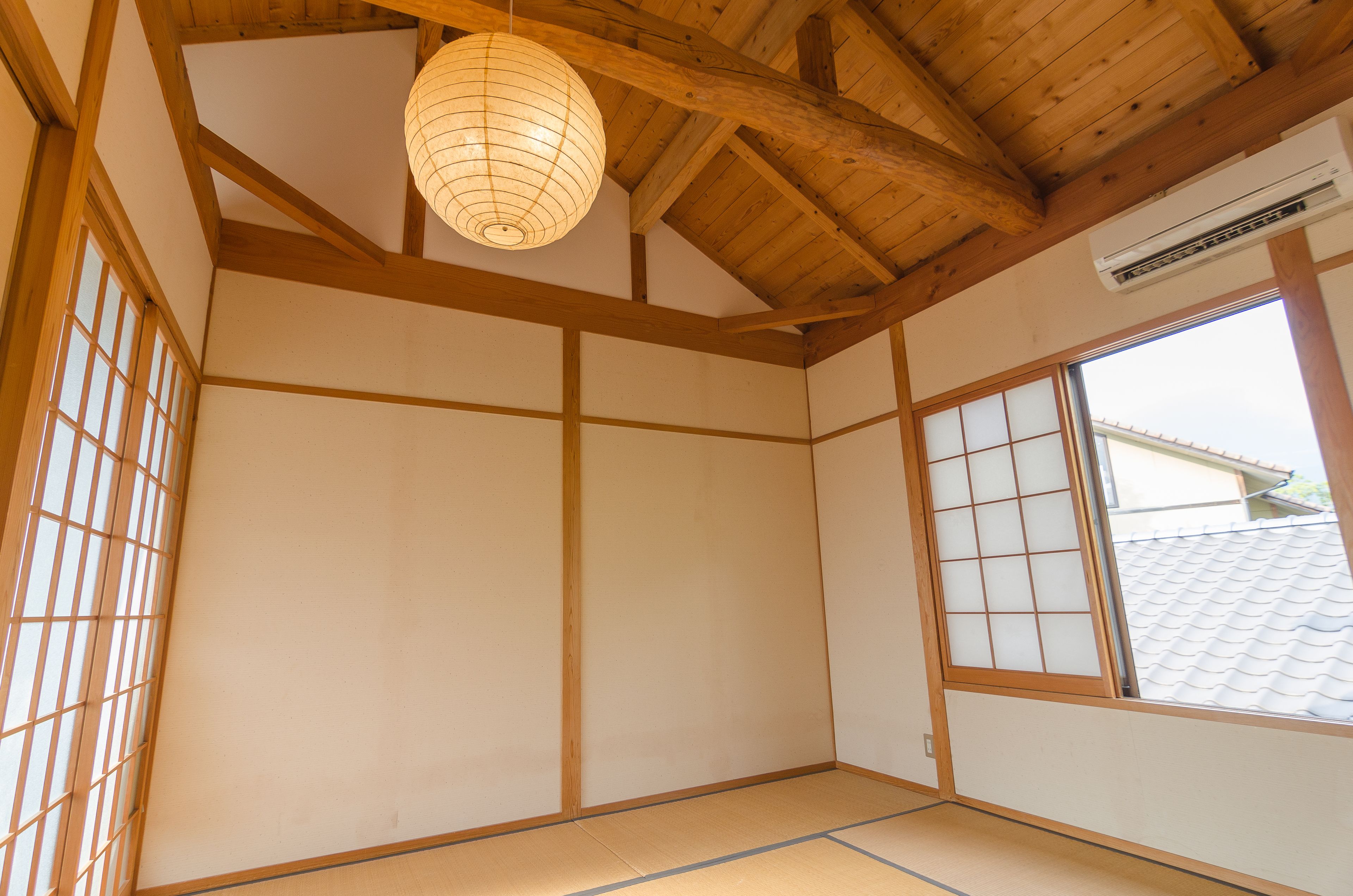 A traditional Japanese room with tatami flooring, shoji screens, and a wooden ceiling.
