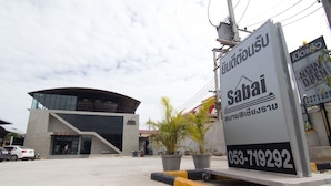A modern hotel with a curved facade, a large entrance, and a signboard advertising the hotel. - Sabai@Chiang Rai (Chiang Rai)