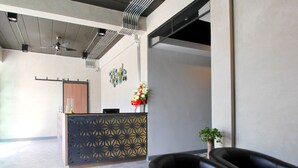 A reception area with a modern design, including a patterned partition, a reception desk, and a seating area with a black sofa. - Sabai@Chiang Rai (Chiang Rai)