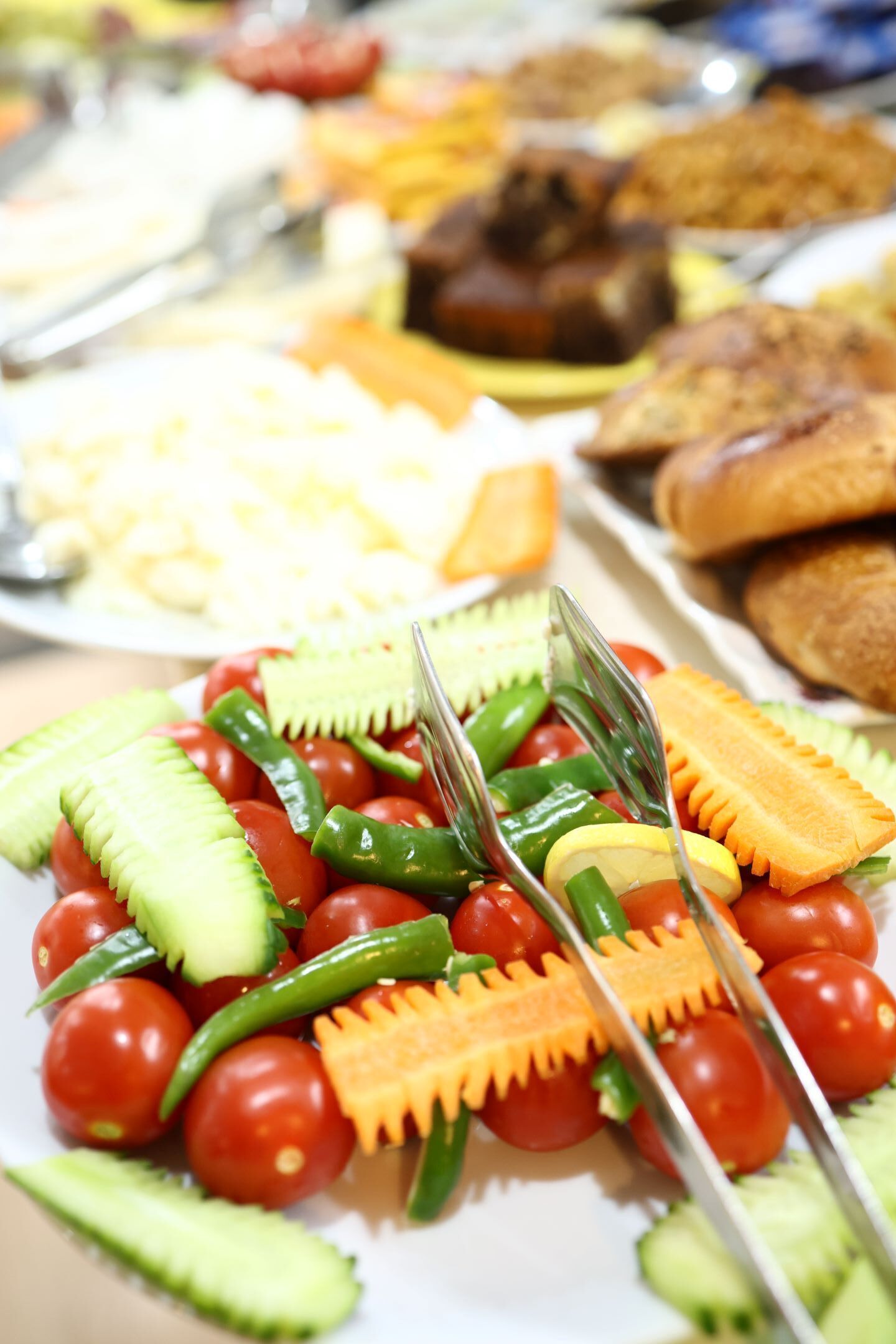 Een buffet met diverse soorten eten, zoals tomaten, komkommers en groene paprika's.