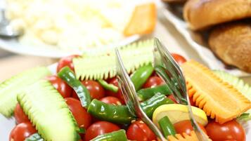 Een buffet met diverse soorten eten, zoals tomaten, komkommers en groene paprika's.
