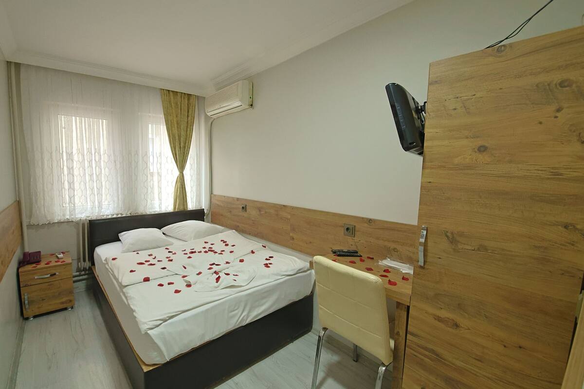 Una habitación de hotel con cama, mesita de noche y un armario de madera.
