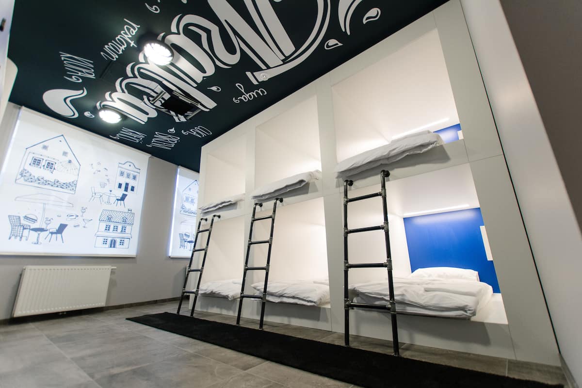 Ein Hotelzimmer mit Etagenbetten, schwarzem Teppich und einem weißen Heizkörper.