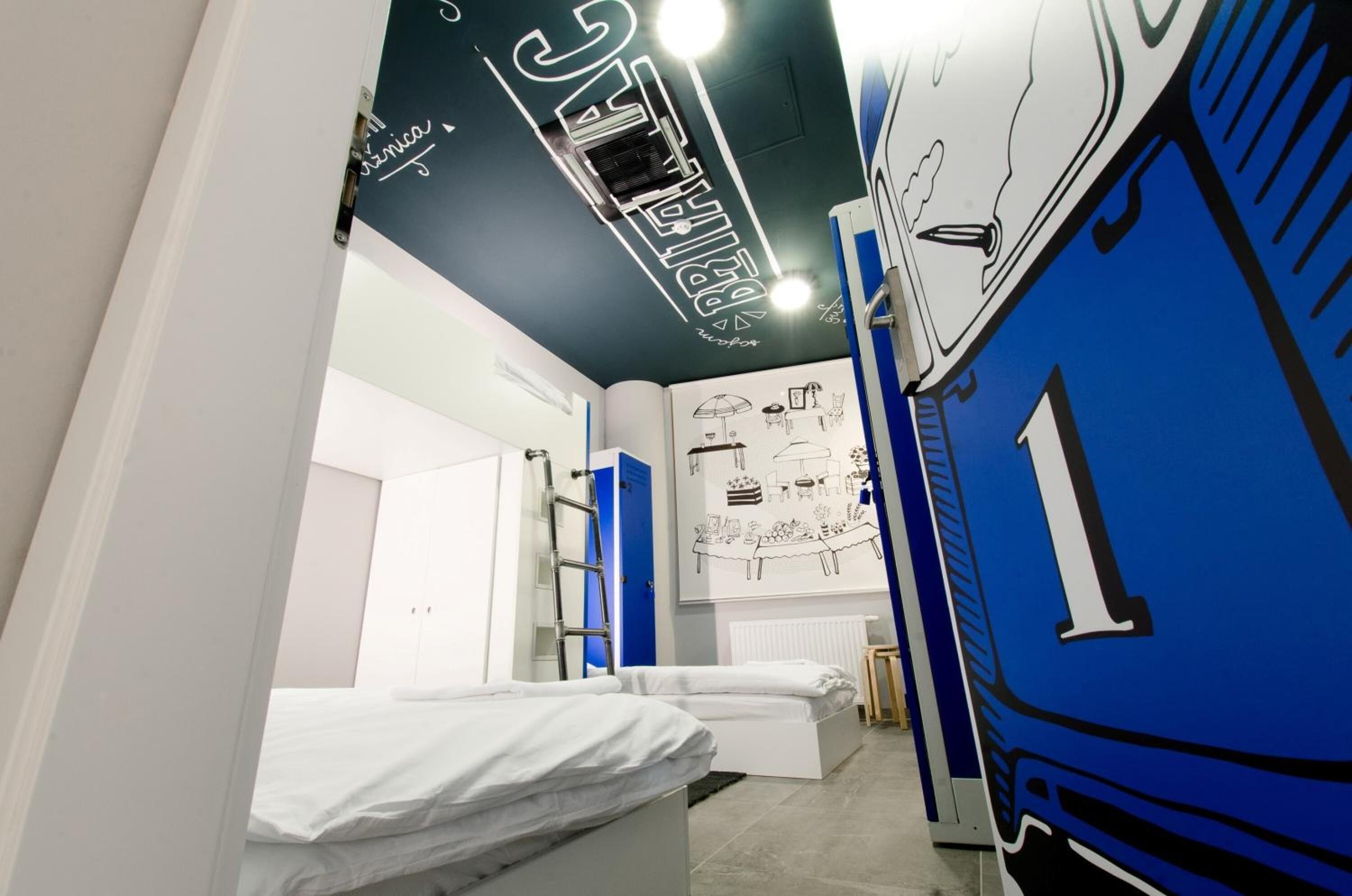 A room with two beds, a ladder, a radiator, and a wall with a large number '1'.