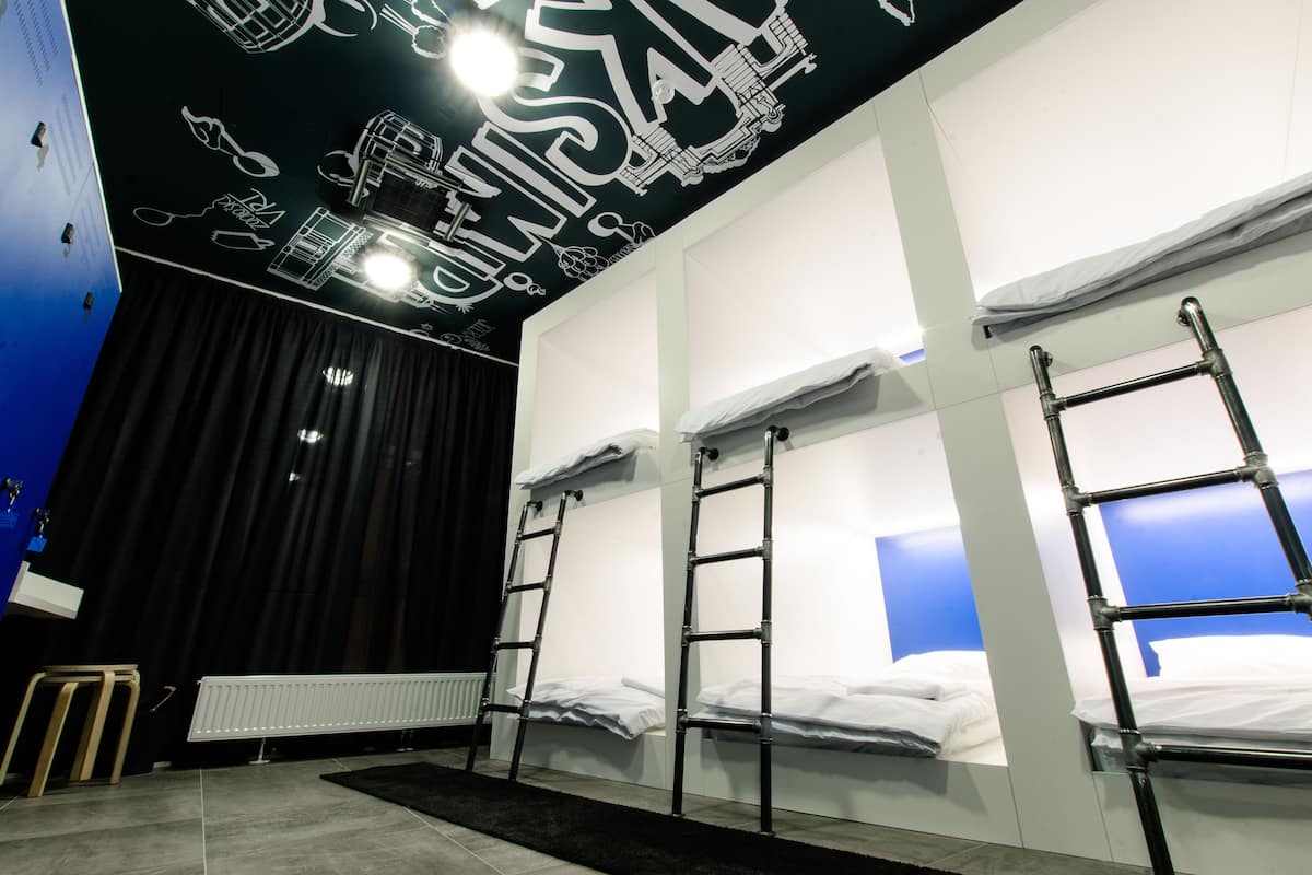 Ein Zimmer mit Stockbetten, einem Heizkörper und einem schwarzen Vorhang.