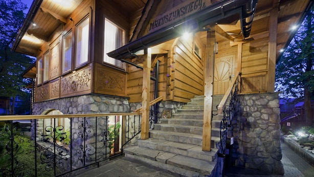A wooden building with a stone facade, a staircase, and a metal railing.