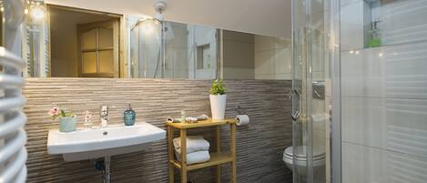 A modern bathroom with a skylight, a sink with a wooden shelf, a toilet, and a glass shower enclosure.