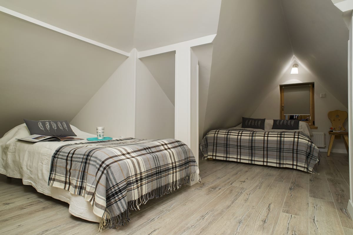 Une chambre avec deux lits, un miroir et une petite table avec une lampe.