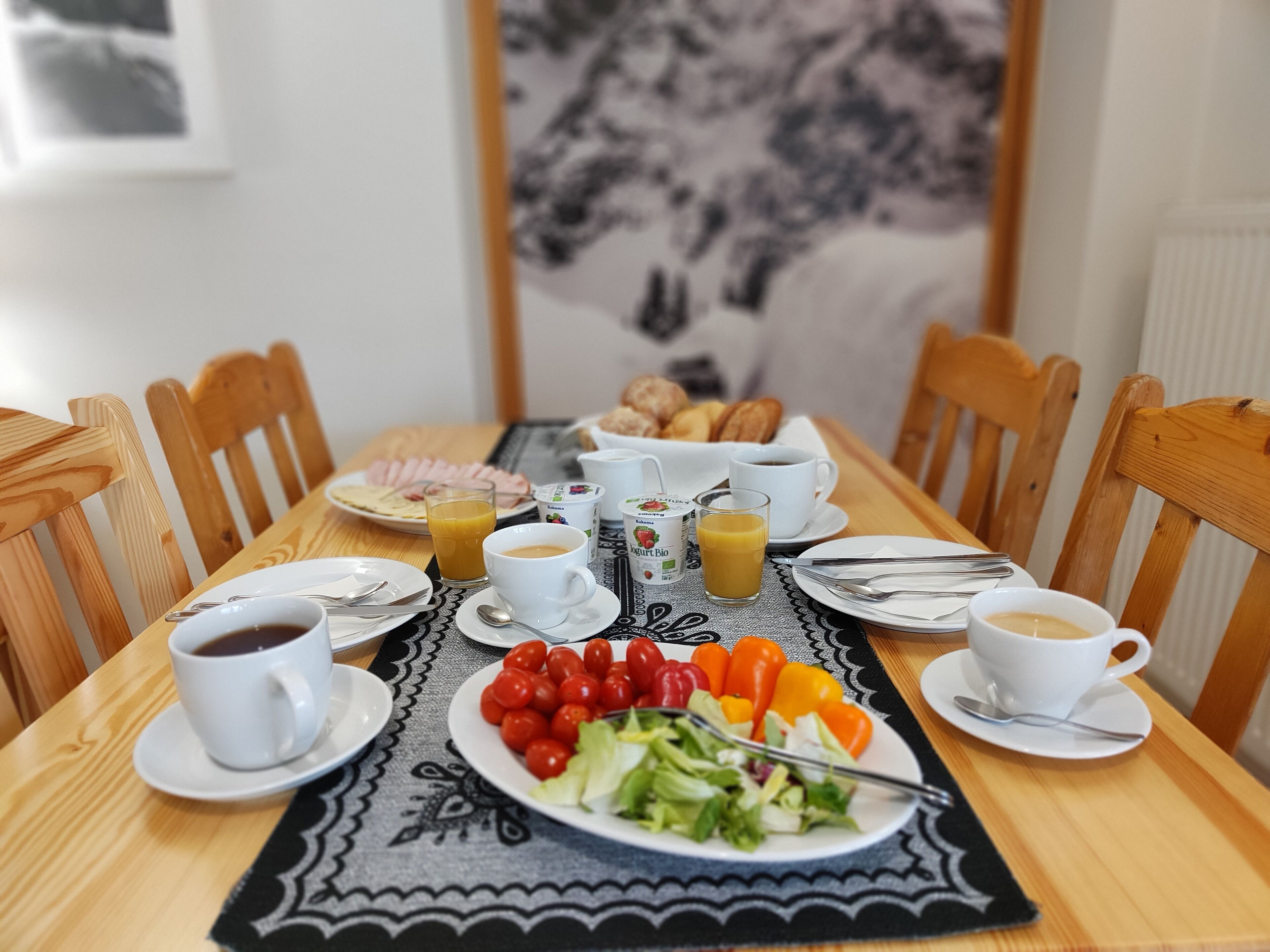 Une table de petit-déjeuner dressée avec des assiettes remplies de nourriture, des tasses de café et des verres de jus de fruits.