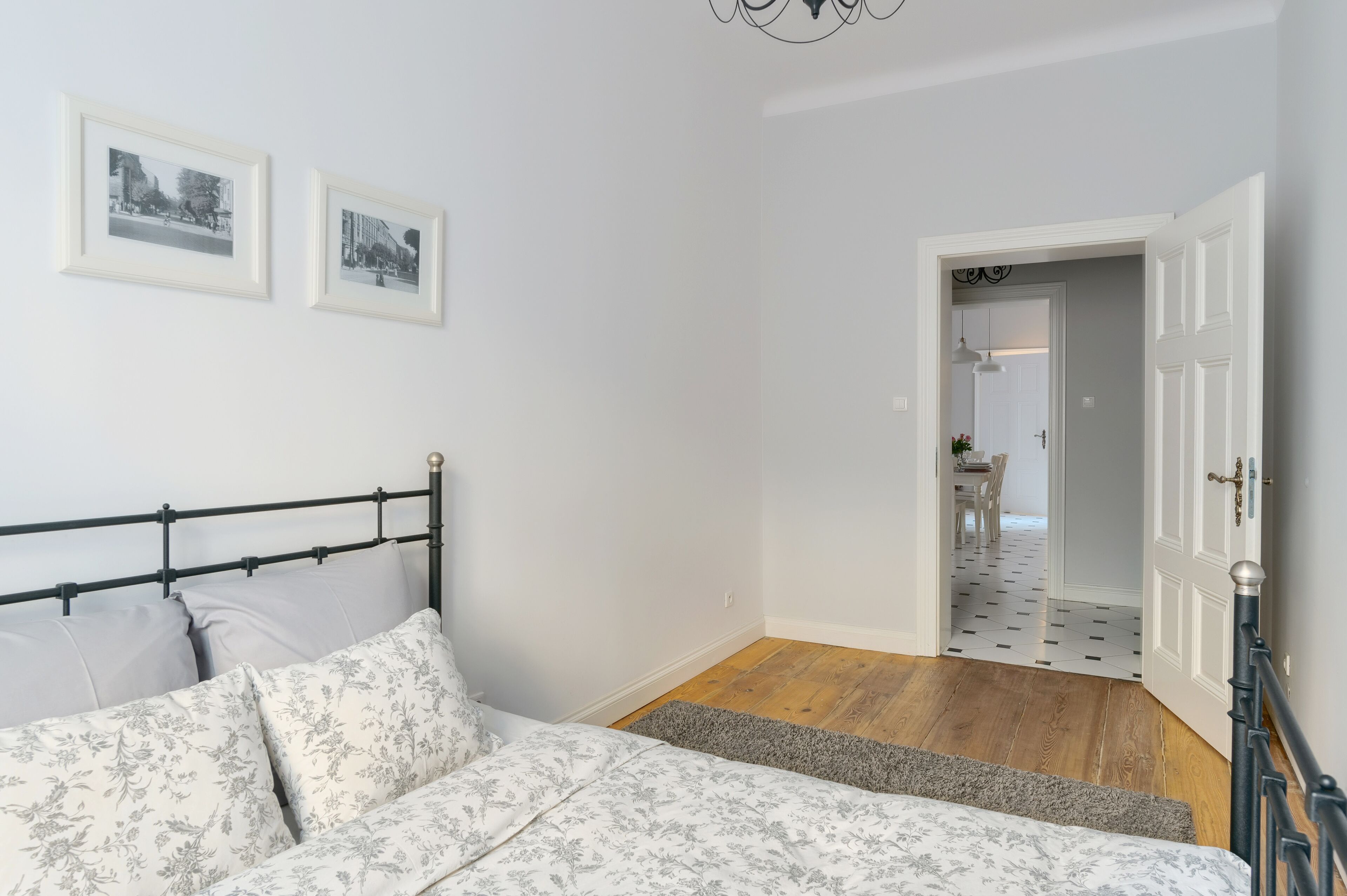 A bedroom with a bed, a nightstand, and a door leading to a hallway.