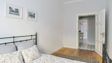 A bedroom with a bed, a nightstand, and a door leading to a hallway.
