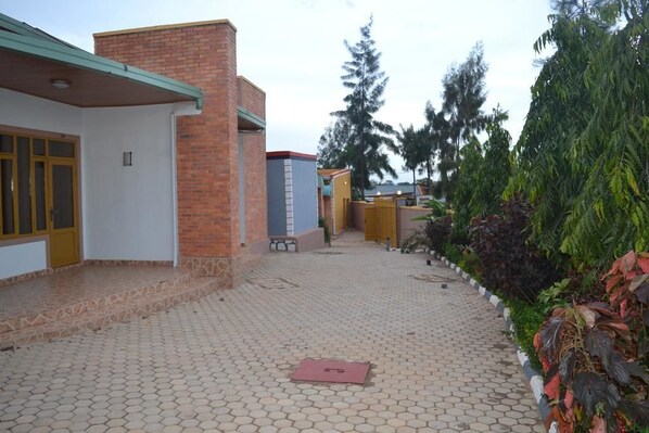 A courtyard with a paved walkway, a brick building, and a bench.