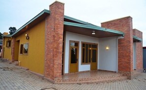 A two-story building with a yellow facade, brick chimneys, and a covered entrance with glass doors.