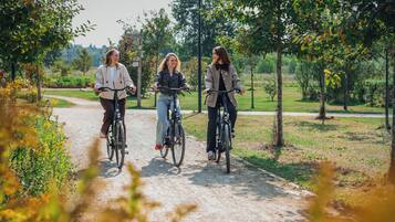 Tre persone in bicicletta su un sentiero immerso tra alberi e vegetazione.