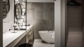 A modern bathroom with a freestanding bathtub, a large mirror, and a towel rack.