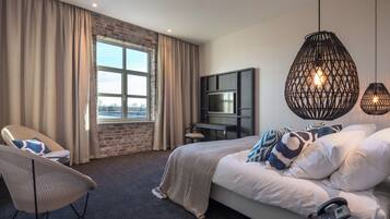 Una habitación de hotel con una cama grande, televisión, escritorio y una silla.
