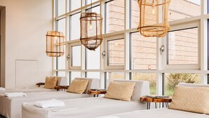 Habitación de hotel con ventanas amplias, varias camas y lámparas colgantes de mimbre.