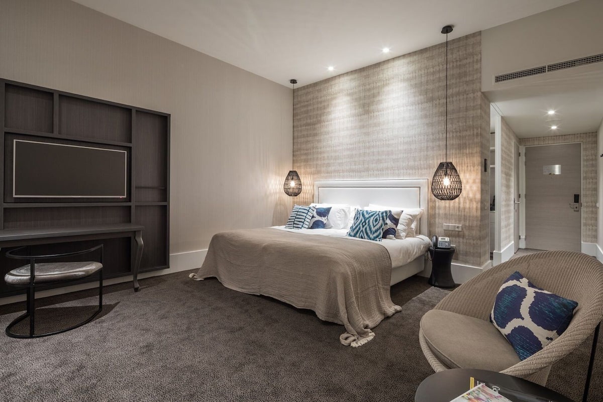 Una habitación de hotel moderna con una cama grande, un escritorio y una zona de estar.