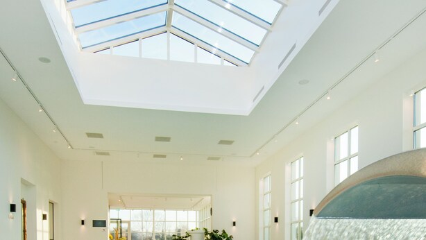 Una gran piscina interior con tragaluces, una cascada y plantas en macetas.