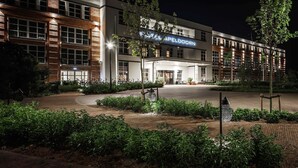 Un hotel con diseño moderno, destacando una entrada imponente y una fachada bien iluminada.