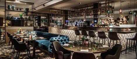 A modern bar area with a bar counter, seating, and shelves stocked with bottles.