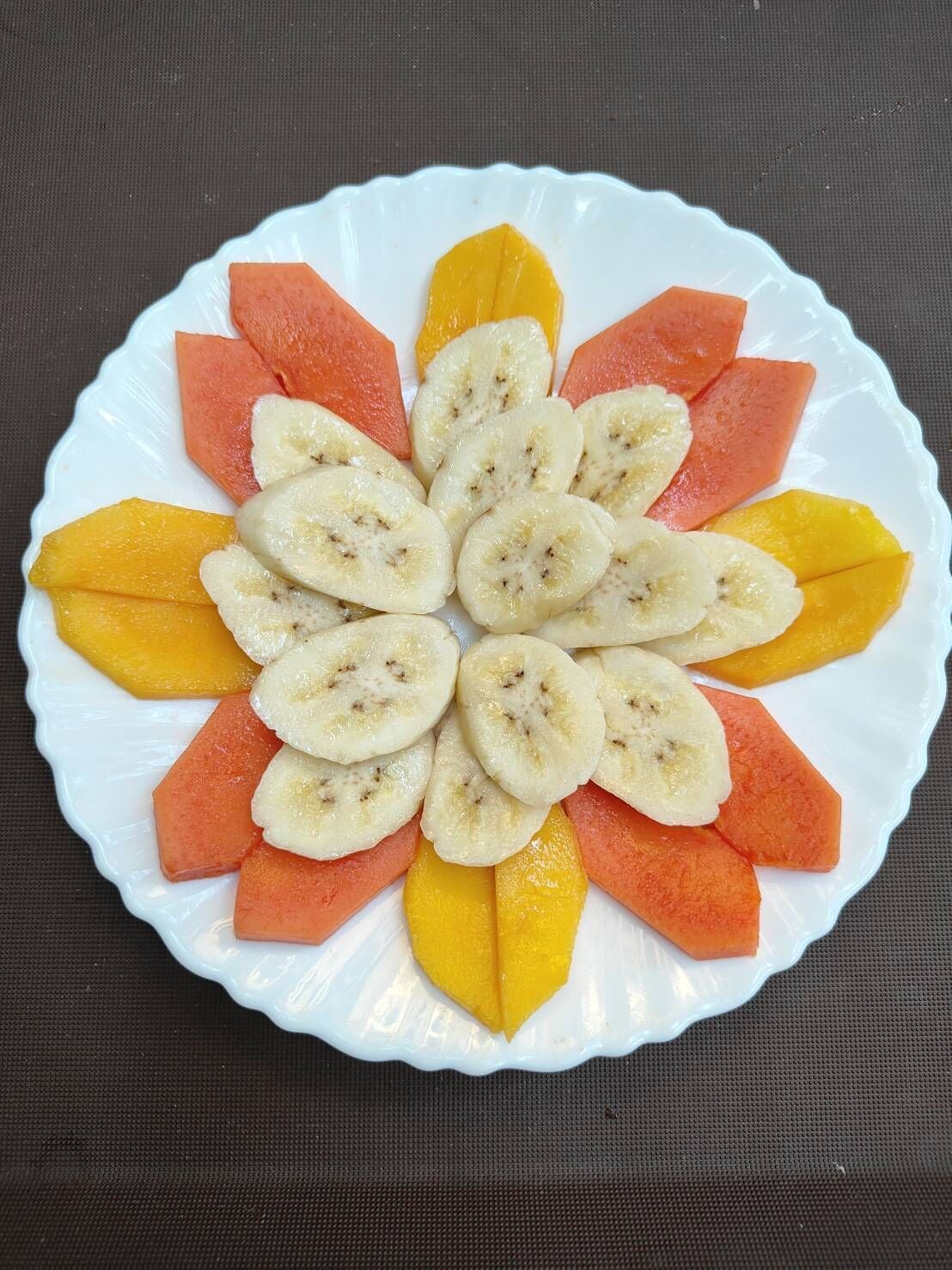 Ein weißer Teller mit Obstscheiben, die kreisförmig angeordnet sind.