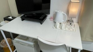 A hotel room with a white desk, a black television, a white kettle, a tray with cups, a trash bin, and a small refrigerator. - Hotel Royal Oak Gotanda (Tokyo)